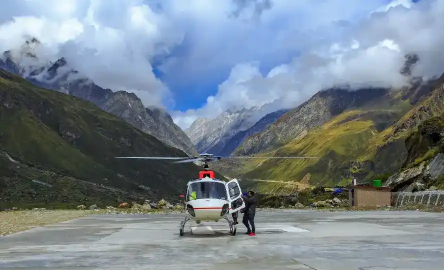 Pilgrim boarding helicopter at Himalayan helipad surrounded by mountain ridges